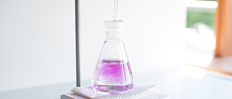 Nahaufnahme einer Titration, die Lösung färbt sich langsam rosa